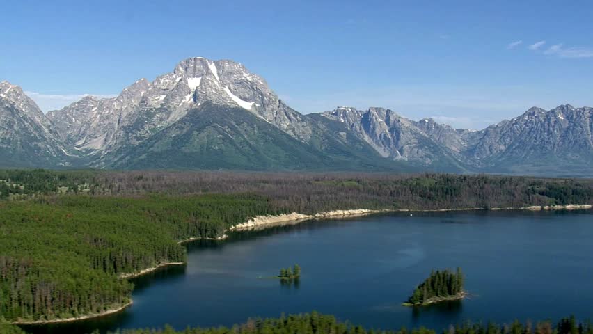 Grand Teton mountains reflecting in Jackson Lake under a clear blue summer sky