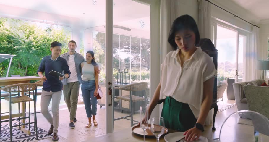 Korean host placing plate on table by glass door, welcoming friends entering carrying tray for meal. Hospitality, gathering, celebration, camaraderie, indoors, outdoor, cheerful