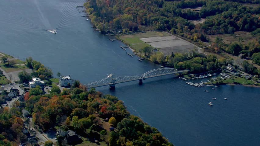 Aerial view of a bridge spanning a wide river surrounded by colorful autumn trees