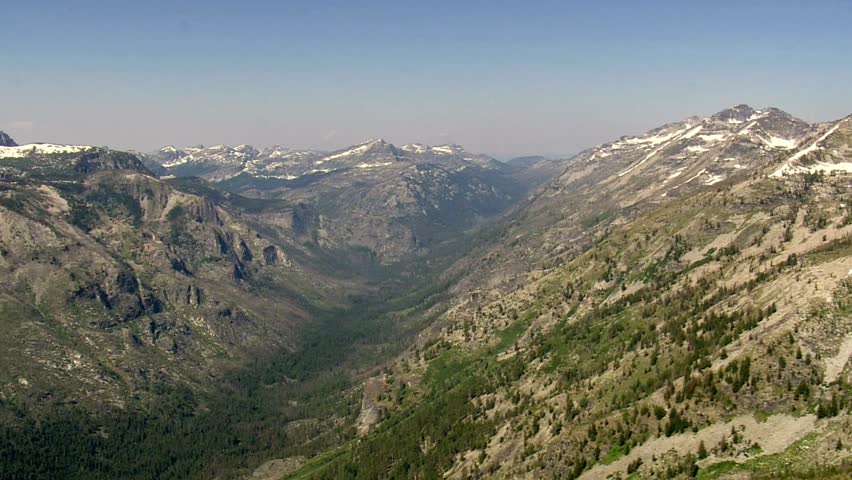 Scenic mountain valley landscape with snowcapped peaks under a clear blue sky