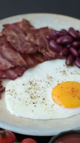 Fried egg, bacon and beans, a classic British breakfast with tomatoes. Egg, bacon and beans