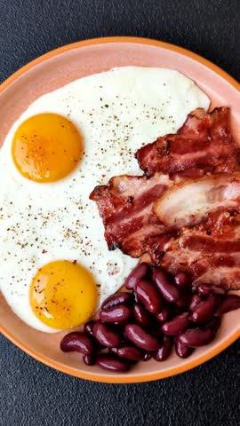 Fried egg, bacon and beans, a classic British breakfast with tomatoes. Egg, bacon and beans