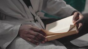 Man in white robe holding open book, reading calmly while sitting on floor in peaceful bedroom. Soft sunlight filters through window, creating serene, relaxed atmosphere for quiet reflection - Powered by Shutterstock - Get 15% off with code: PIKWIZARD15
