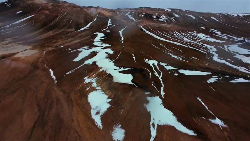 FPV drone footage capturing the surreal geothermal landscape of Hverir in North Iceland. The video showcases steaming fumaroles, bubbling mud pools, and mineral-rich terrain with vivid earth tones.