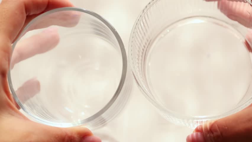 Clinking of transparent glass cups, top view, close-up of sound and motion.