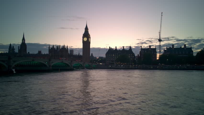 Dramatic timelapse capturing the stunning London skyline with Big Ben and the Houses of Parliament silhouetted against a beautiful sunset sky as evening transitions into night over the River Thames
