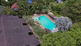 an orbit drone shot of a man swimming in a pool at a tropical resort surrounded by palms and greenery - Powered by Shutterstock - Get 15% off with code: PIKWIZARD15