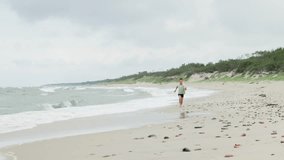 A joyful child runs energetically along the beach, enjoying the waves and sandy shore on a cloudy day - Powered by Shutterstock - Get 15% off with code: PIKWIZARD15