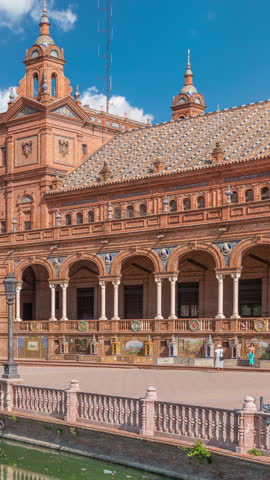Plaza de Espana in Seville timelapse, a grand architectural complex in Maria Luisa Park built for the Ibero-American Exposition. Arches, canal and red walls under blue cloudy sky.