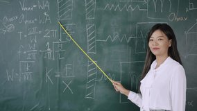 Back to school in summer. Happy Asian young female math teacher standing holding a pointer and teaching a mathematics lesson on blackboard in front of the classroom, Concept of learning and education. - Powered by Shutterstock - Get 15% off with code: PIKWIZARD15