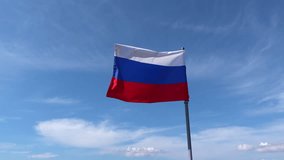 National tricolor flag of Russia waving in the wind on a flagpole. The white, blue, and red banner is a symbol of the Russian Federation against a beautiful blue sky with white clouds - Powered by Shutterstock - Get 15% off with code: PIKWIZARD15