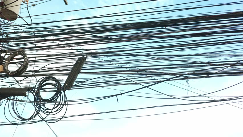 Silhouetted tangled lines appear under cloudy weather, lines contrasting sky, lines showing urban clutter. Dark outlines and atmospheric mood. Great for environmental impact concept stories.