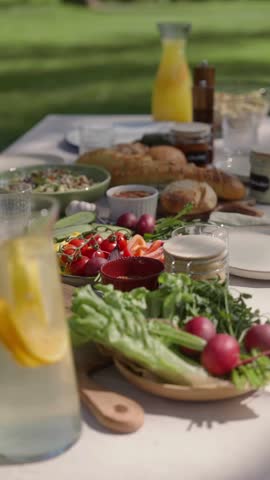Close up of lemonade jar at brunch table, refreshing citrus drink with ice and mint leaves, summer outdoor breakfast beverage served in natural daylight 4K Ultra HD video