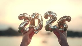 Hands holding golden balloon numbers 2026 with sunset light, happy new year celebration and future concept, hope and success idea for holiday greeting and new beginning with warm golden atmosphere - Powered by Shutterstock - Get 15% off with code: PIKWIZARD15