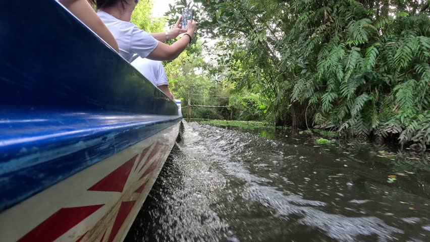 Hoi An, Vietnam - October 14th 2025: Tourists on a small boat on a river with water plants in Vietnam 