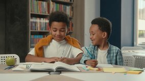 Two little boys African American siblings children learning at desk smiling happy kids studying together schoolboys pupils students primary school talk write task education homework lesson book study - Powered by Shutterstock - Get 15% off with code: PIKWIZARD15