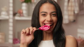 Smiling Latina woman ethnic cheerful happy Hispanic female teen pampering attractive girl bite candy eating sweets diet healthcare smile toothy dental oral care beauty cosmetics ads in pink bathroom - Powered by Shutterstock - Get 15% off with code: PIKWIZARD15