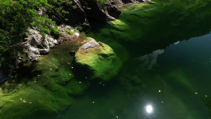 Drone view of Dos Aguas’ river narrowing between large rock formations and green foliage. Perfect for nature-driven storytelling