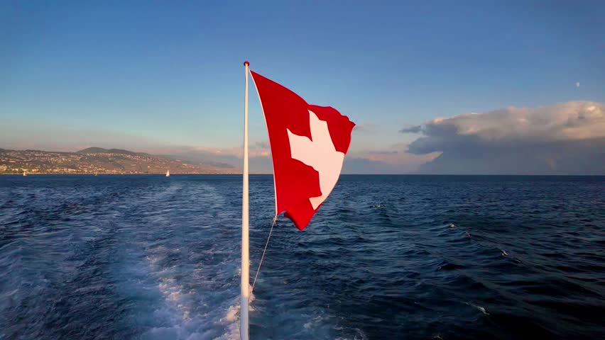Real time of 4K Swiss National Flag Waving Over Lake Geneva at Sunset, Switzerland.