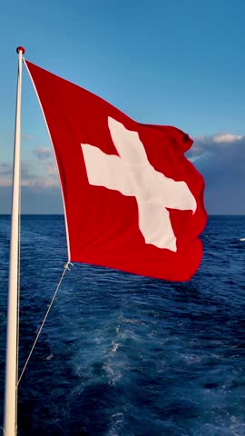 Real time of 4K Swiss National Flag Waving Over Lake Geneva at Sunset, Switzerland.