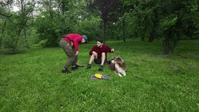 Man and woman resting on grass with Australian Shepherd dog after playtime with frisbee and puller toys in park. 4k footage. - Powered by Shutterstock - Get 15% off with code: PIKWIZARD15