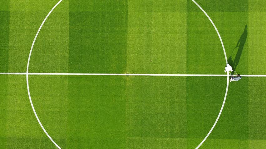Ascending top-down view of painting the center circle of the Ipurua football field.