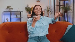 Smiling young Caucasian woman making phone conversation with friends sitting on sofa couch at home in room. Happy excited girl enjoying mobile loudspeaker talking gossiping at modern home apartment - Powered by Shutterstock - Get 15% off with code: PIKWIZARD15