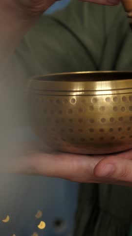 Woman using stick and singing bowl. Yoga and meditating concept. Closeup. Vertical footage