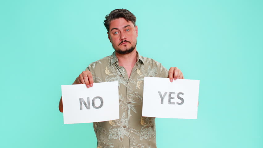 Middle-aged man holds yes and no signs, offering clear choice or opportunity for decision-making, directly looking into camera. Young adult guy on blue background emphasizing clear options selection