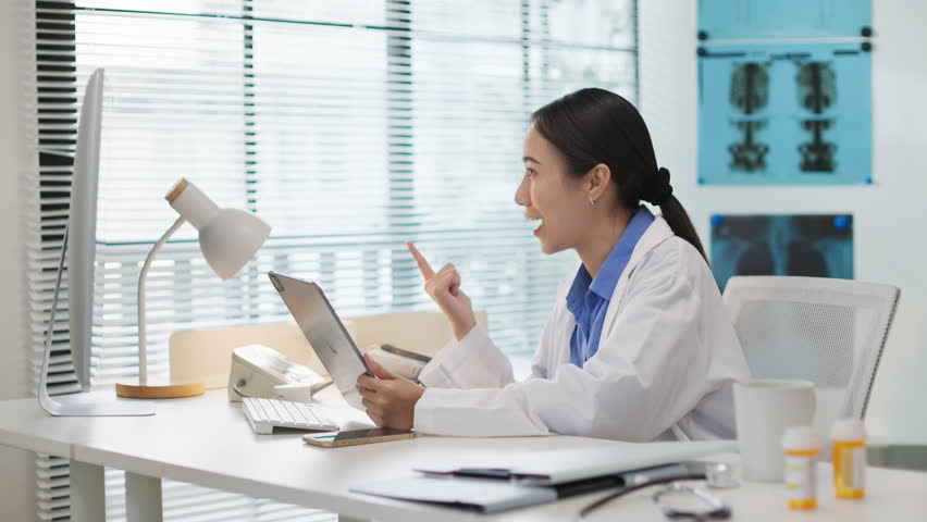 Asian female doctor doing online consultation, remote healthcare, virtual medical advice to patient via video call in hospital or clinic. Telemedicine, digital healthcare services, online diagnosis.