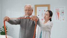 Asian female physiotherapist helps an elderly man perform resistance band exercises for physical therapy in a modern clinic, promoting rehabilitation, strength training, and active aging support. - Powered by Shutterstock - Get 15% off with code: PIKWIZARD15