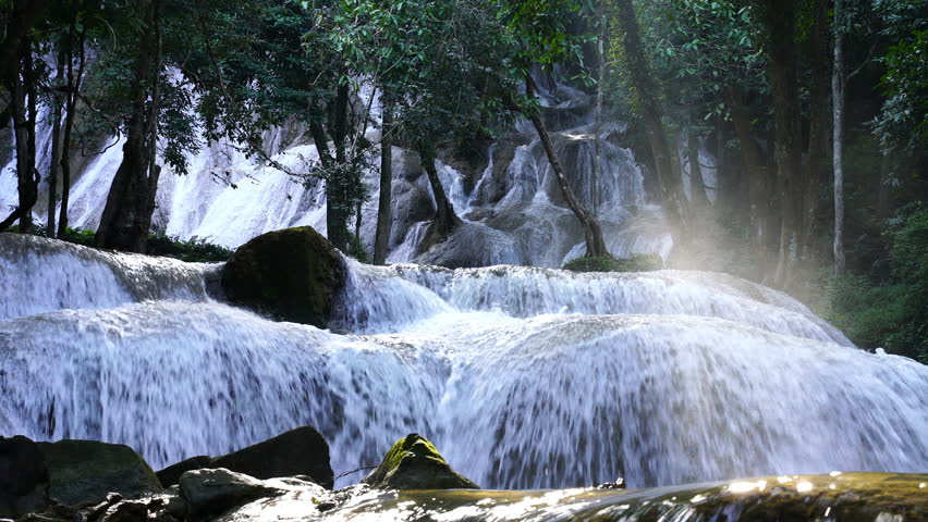 Tropical waterfall cascading over rocky cliff surrounded by lush forest, showcasing raw nature and untouched beauty. Ideal for eco-tourism content, documentaries, and travel visuals.
