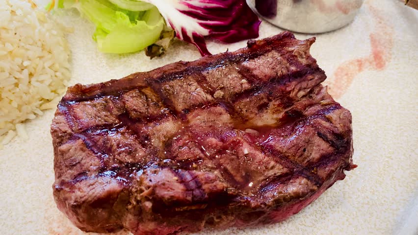 Juicy medium rare beef steak with cheese sauce and salad served in elegant restaurant setting