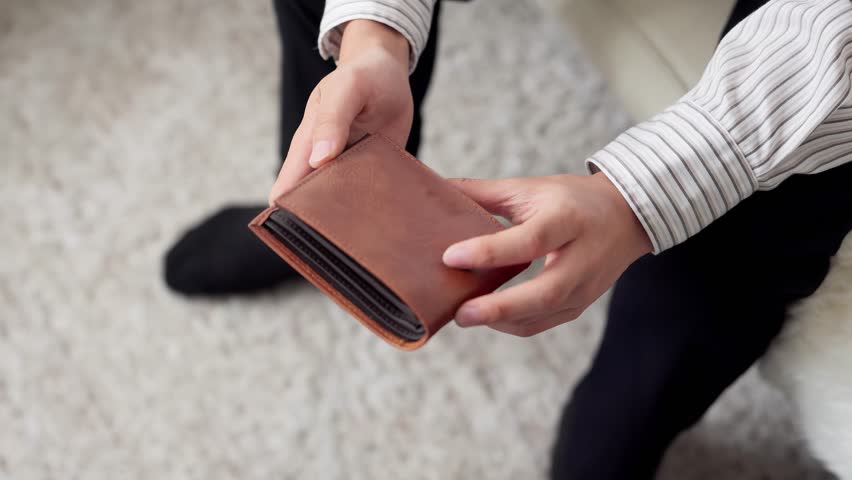 Checking his wallet. A poor student with no money.