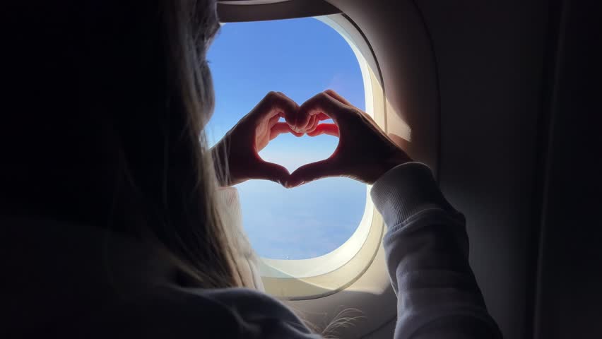 Heart shaped hands capture a sincere gesture through an airplane window with bright blue sky  - Powered by Shutterstock - Get 15% off with code: PIKWIZARD15