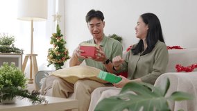 Happy Christmas family couple enjoying presents home, xmas tree brightens cozy living room, people joyful holiday celebration exchanging gifts on couch with warm ambient light, both smiling brightly. - Powered by Shutterstock - Get 15% off with code: PIKWIZARD15