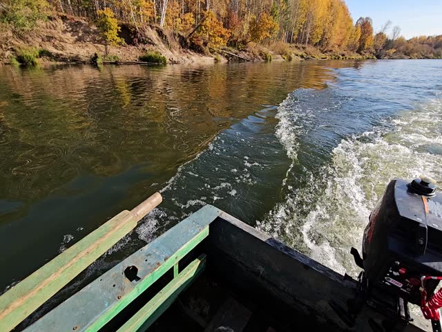 Boat is on the water with a motor. The water is green and the boat is in the middle of the water. woman with phone