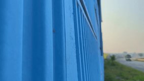Tracking shot beside a blue-painted concrete overbridge wall, revealing texture and depth as vehicles pass on the nearby road under soft morning light. - Powered by Shutterstock - Get 15% off with code: PIKWIZARD15
