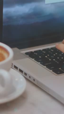 Animation of connected icons over coffee and cropped hands of caucasian man working on laptop. Digital composite, multiple exposure, communication, beverage, drink and technology concept.