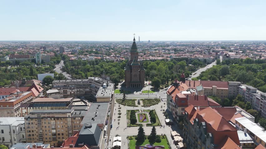 Drone orbiting over city structures, capturing the vast urban layout of Timisoara and the cathedral in the distance.