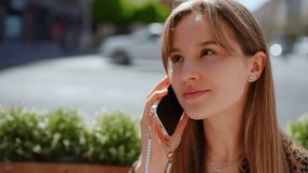 Blonde woman communicating on smartphone while sitting at outdoor cafe, wearing leopard print top and pearl phone chain, radiating cheerful, relaxed urban lifestyle - Powered by Shutterstock - Get 15% off with code: PIKWIZARD15