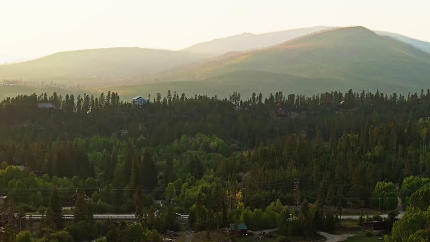 Drone wide tracking right of Grand Lake Colorado marina and surrounding pine hills under soft golden evening light