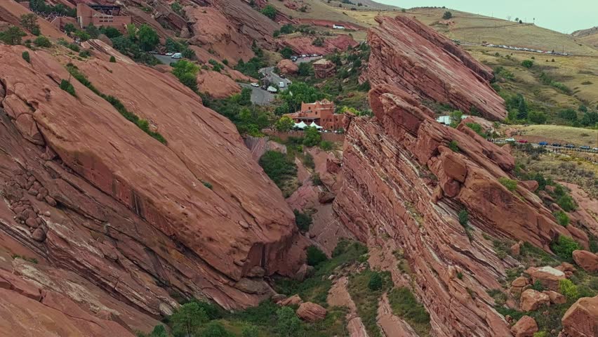 Drone pullback over Red Rocks Amphitheatre Colorado showing distinctive red cliffs and mountain backdrop
