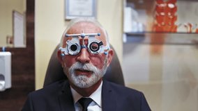 Professional optometrist examining a senior patient's vision with a phoropter trial frame during an appointment in the ophthalmology clinic, selecting the correct lenses for prescription glasses - Powered by Shutterstock - Get 15% off with code: PIKWIZARD15