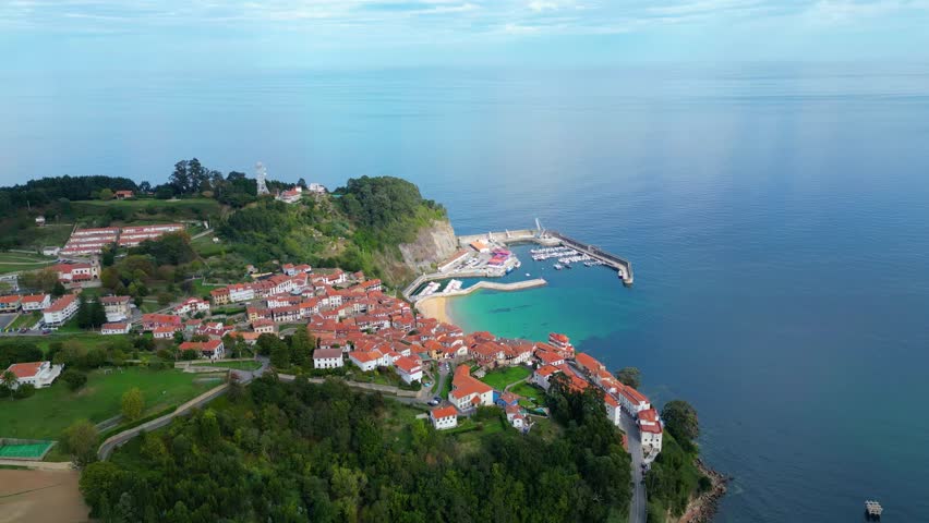 Lastres, Asturias, Spain: A charming fishing village with colorful houses nestled around a vibrant harbor. Captured from above on a bright autumn afternoon.