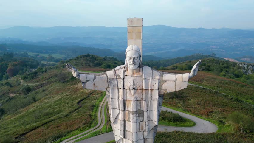 Majestic Christ of Naranco statue overlooking the rolling hills of Asturias, Spain, under a soft afternoon sky. A serene and iconic landmark.
