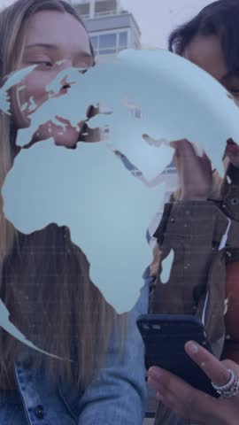 Animation of spinning globe icon over two diverse woman smiling together on the street. Global networking and business technology concept