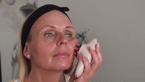 Mature woman using a facial lifting beauty device on her cheek, promoting skin rejuvenation, anti-aging care, and modern home skincare technology for wellness and self-care. - Powered by Shutterstock - Get 15% off with code: PIKWIZARD15