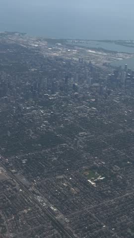 SLOW MOTION SHOT - A handheld shot taken from the window of a plane, flying over the city of Toronto, Ontario, Canada. Aerial scenic daytime view of downtown Toronto from inside an airplane.