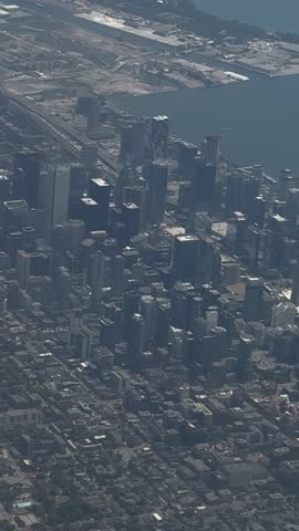 SLOW MOTION SHOT - A handheld shot taken from the window of a plane, flying over the city of Toronto, Ontario, Canada. Aerial scenic daytime view of downtown Toronto from inside an airplane.